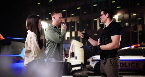 Police officer administering blood test to seated driver during roadside stop