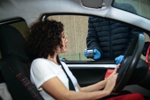 Driver seated in car with window down, viewed from outside vehicle