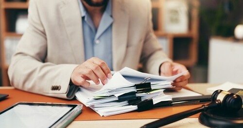 Judge's hands organizing stack of legal documents on office desk