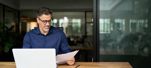 Middle-aged businessman in suit smiling beside office window portrait